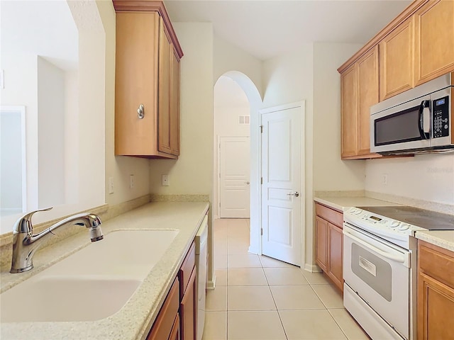 kitchen featuring sink, white appliances, and light tile patterned floors