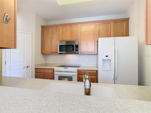 kitchen with sink, light stone counters, and white appliances