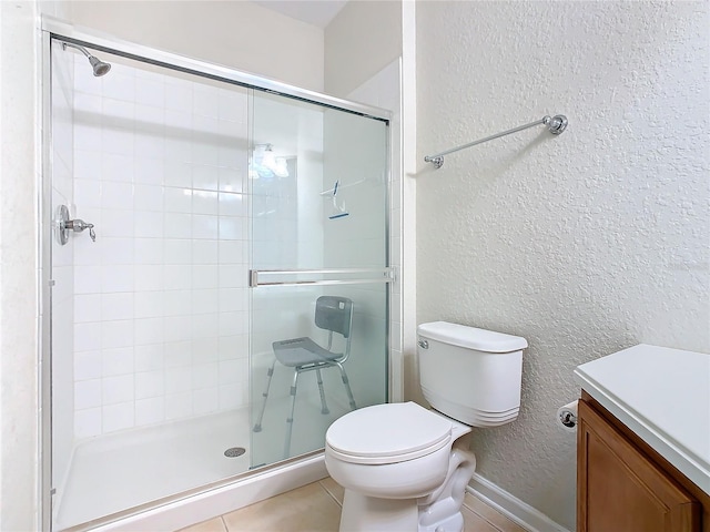 bathroom featuring vanity, toilet, walk in shower, and tile patterned flooring