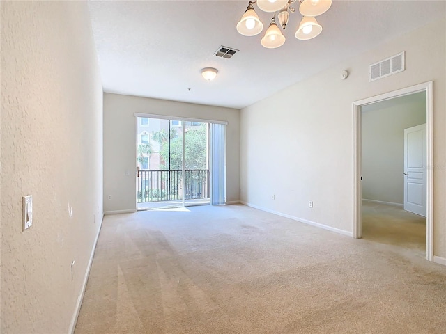 carpeted empty room with an inviting chandelier