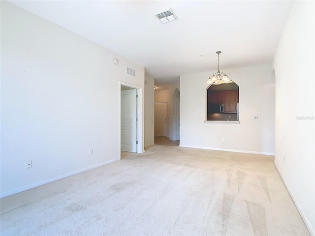 8298 Portofino Dr Unit 202, Davenport, FL 33896 - empty room featuring arched walkways, light carpet, baseboards, and a chandelier
