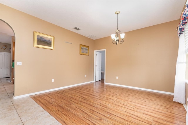 spare room with light wood-type flooring and a chandelier