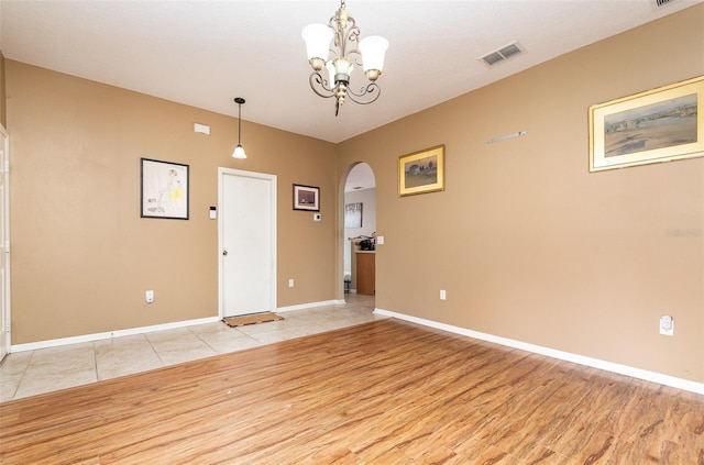 spare room with a chandelier and light hardwood / wood-style floors