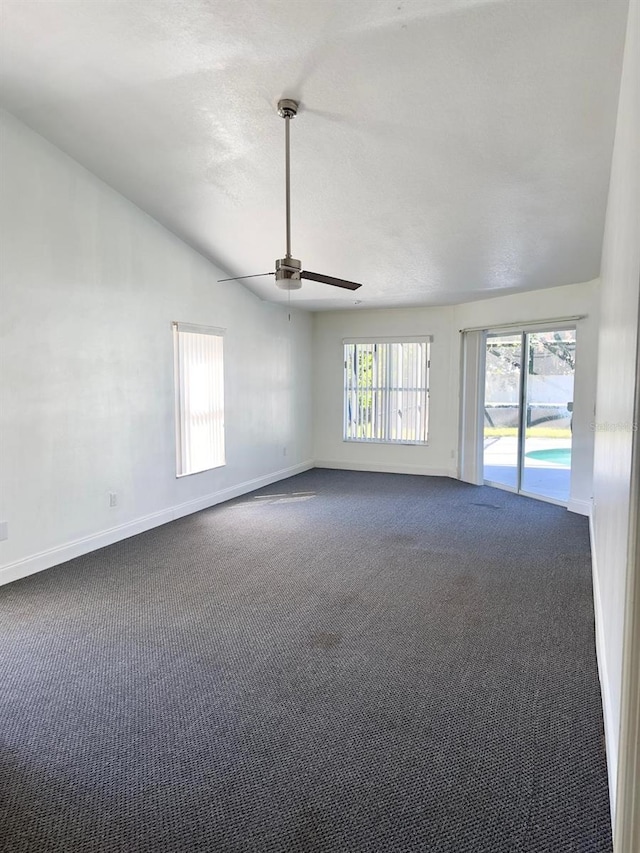 unfurnished room featuring ceiling fan, vaulted ceiling, and dark colored carpet