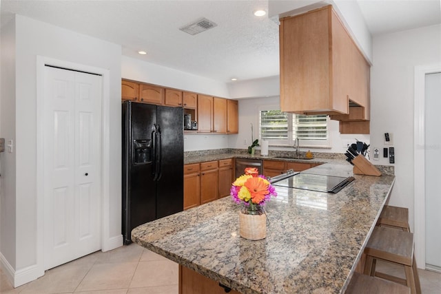 kitchen featuring black appliances, stone countertops, and kitchen peninsula