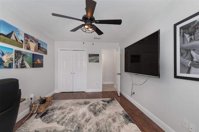 home office featuring a textured ceiling, ceiling fan, and dark wood-type flooring