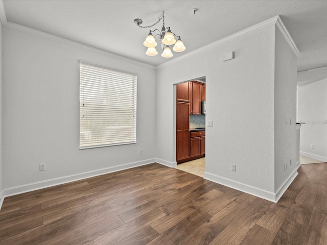 empty room featuring crown molding, a chandelier, and hardwood / wood-style flooring