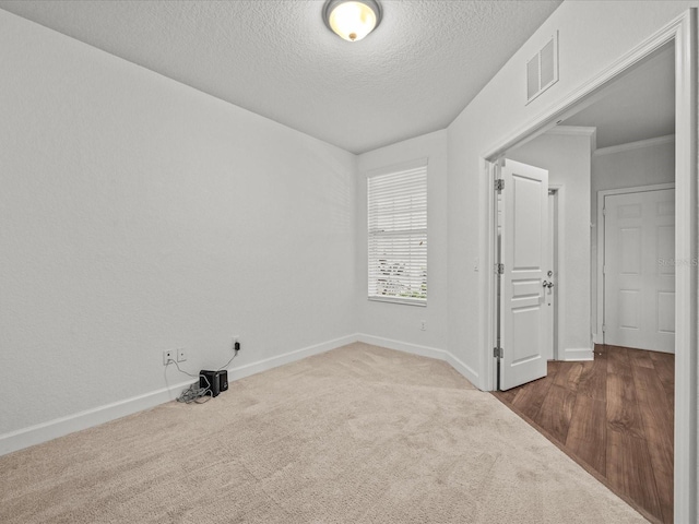 carpeted empty room featuring a textured ceiling and ornamental molding