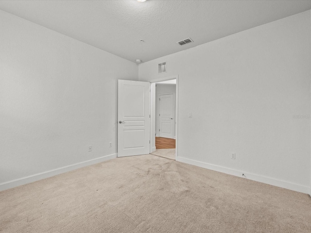 carpeted empty room featuring a textured ceiling and vaulted ceiling