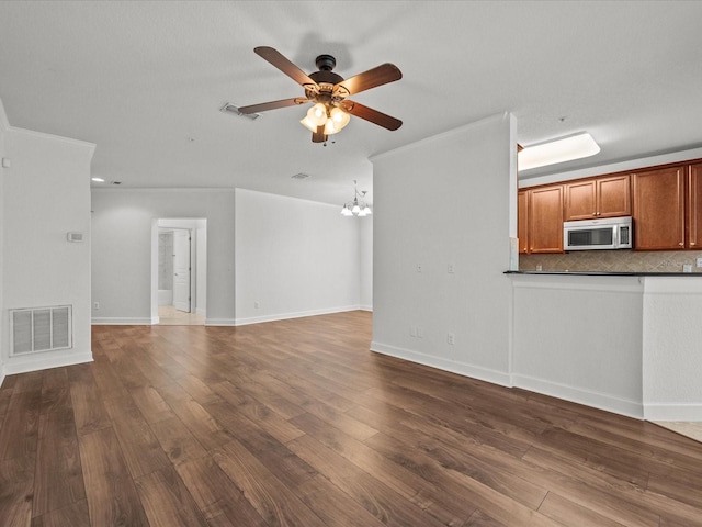 unfurnished living room featuring dark hardwood / wood-style floors and ceiling fan with notable chandelier