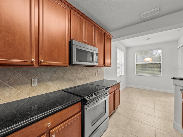 kitchen featuring backsplash, light tile patterned flooring, stainless steel appliances, and dark stone counters