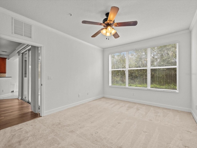 spare room with crown molding, ceiling fan, light colored carpet, and a textured ceiling