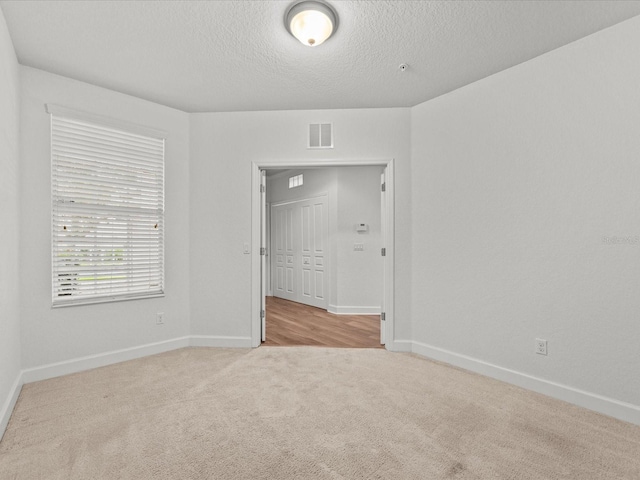 unfurnished room with light carpet and a textured ceiling