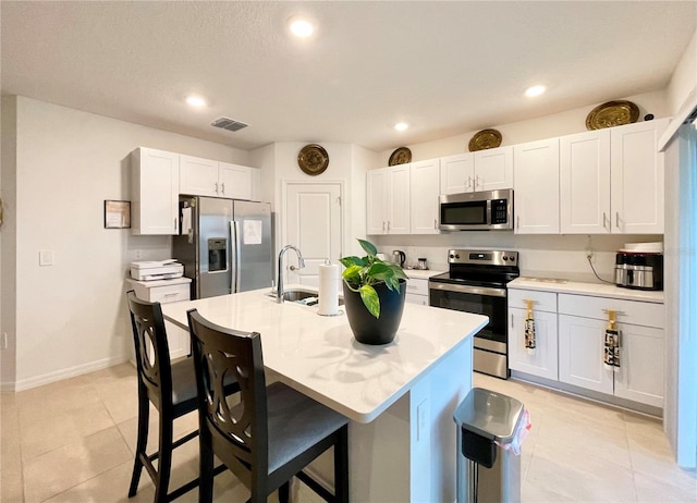 kitchen with a center island with sink, stainless steel appliances, sink, and white cabinetry