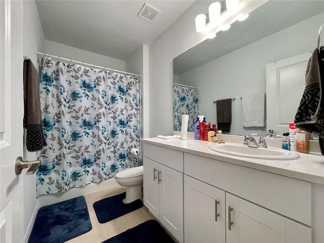 bathroom with a textured ceiling, tile patterned floors, vanity, and toilet