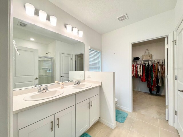 1393 Asher Mason Ave, Kissimmee, FL 34744 - bathroom with a shower stall, double vanity, a walk in closet, tile patterned floors, and baseboards