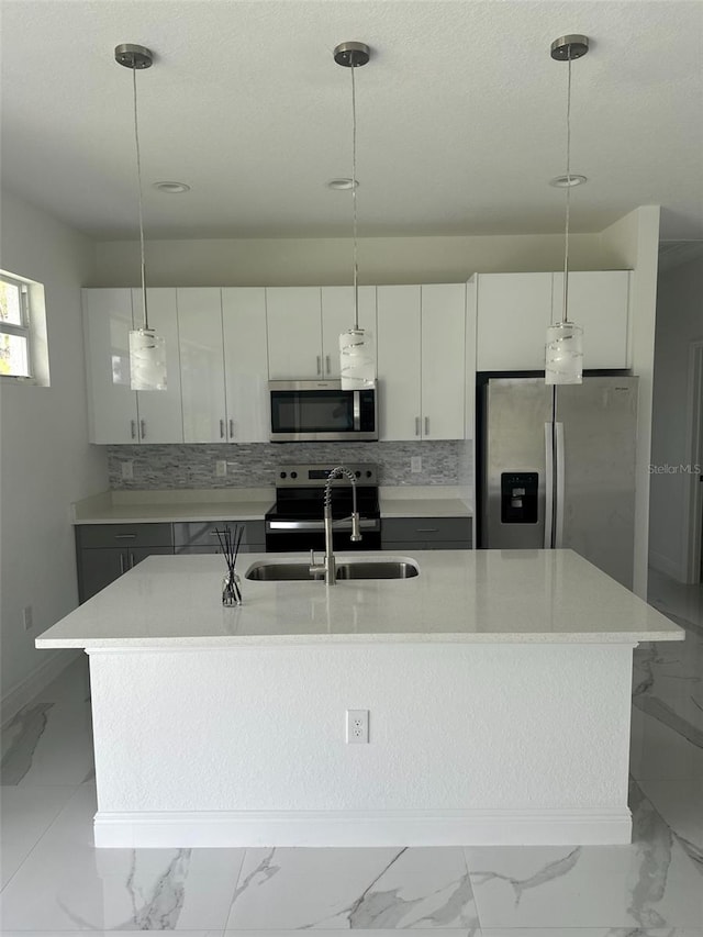 kitchen featuring a kitchen island with sink, hanging light fixtures, white cabinetry, and stainless steel appliances