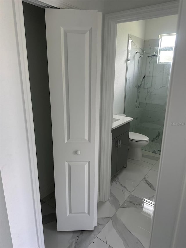 bathroom featuring a tile shower, toilet, and vanity