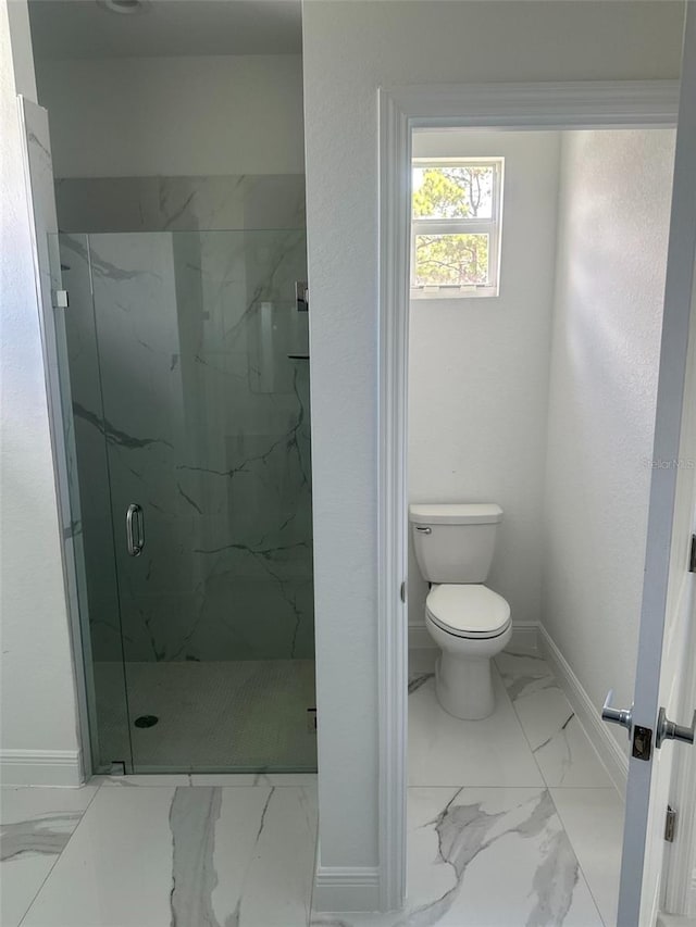 bathroom featuring a shower with shower door and toilet