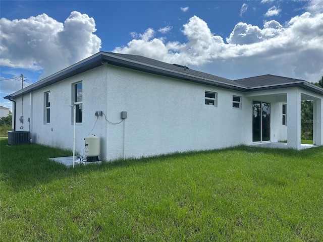 back of house with cooling unit and a yard