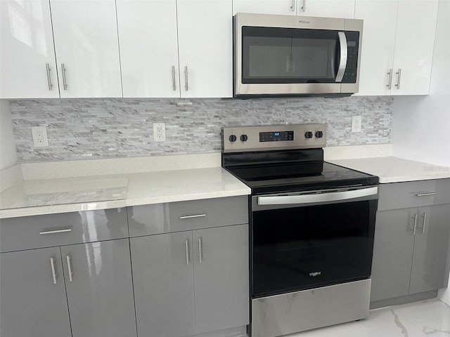 kitchen with tasteful backsplash, gray cabinets, stainless steel appliances, and white cabinets