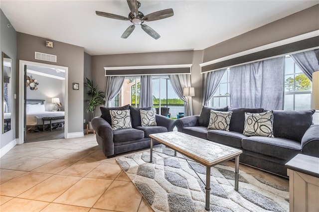 living room featuring baseboards, a ceiling fan, visible vents, and light tile patterned floors
