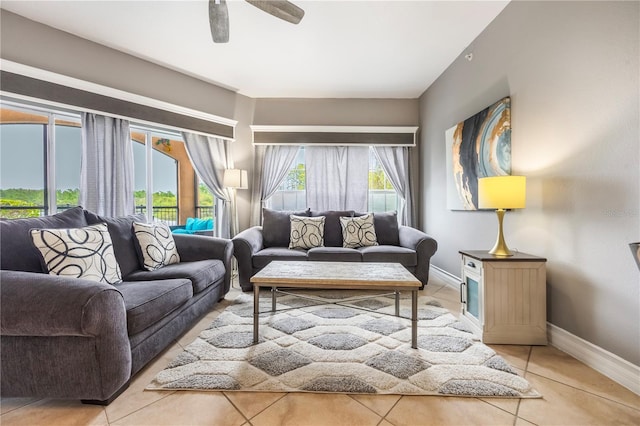 living area featuring light tile patterned flooring, a ceiling fan, and baseboards