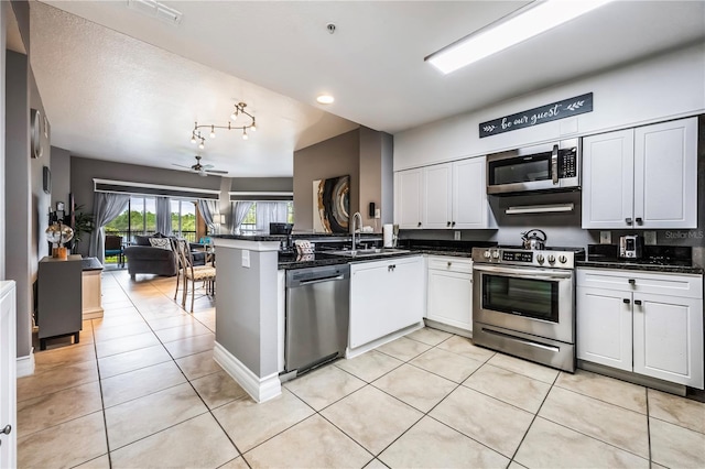 kitchen featuring a peninsula, a sink, open floor plan, visible vents, and appliances with stainless steel finishes