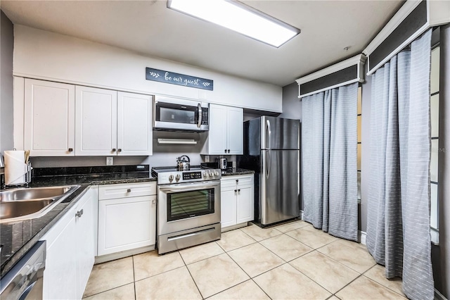 kitchen with sink, appliances with stainless steel finishes, white cabinetry, and light tile patterned floors