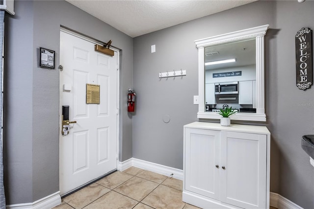 entryway with visible vents, baseboards, a textured ceiling, and light tile patterned floors