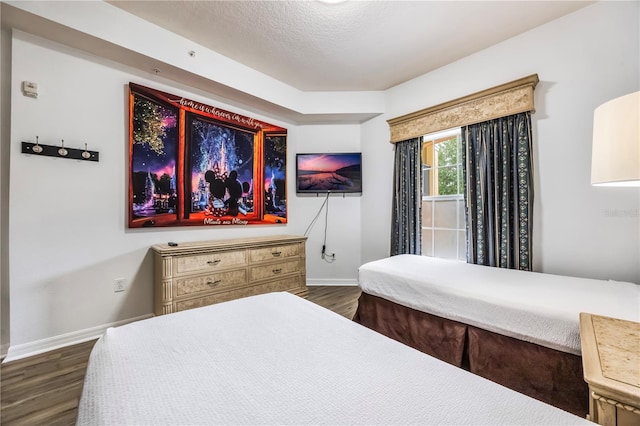 bedroom with a textured ceiling and dark hardwood / wood-style floors