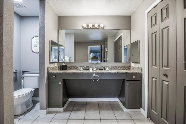 bathroom featuring vanity, toilet, tile patterned floors, and a textured ceiling