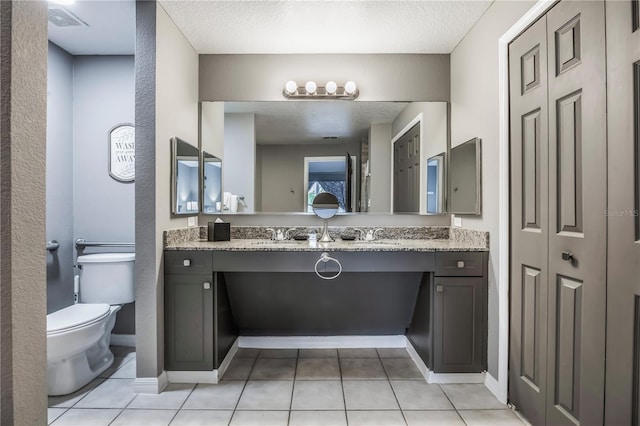 bathroom with tile patterned flooring, visible vents, toilet, vanity, and a textured ceiling