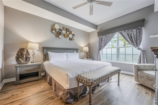 bedroom featuring baseboards, wood finished floors, and ceiling fan