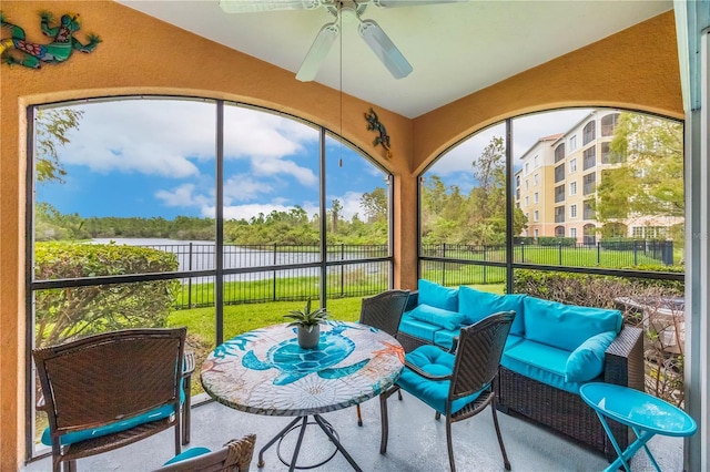 sunroom featuring a ceiling fan, a water view, and an outdoor living space