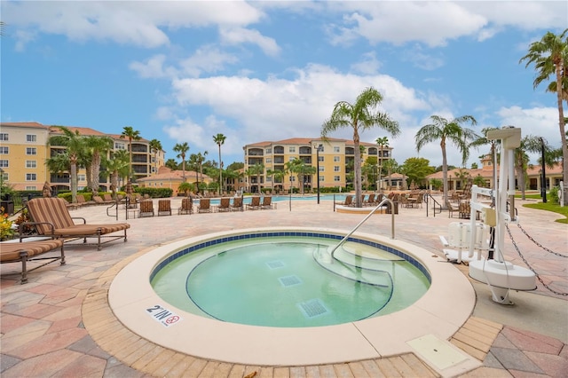 pool with a patio area and a hot tub