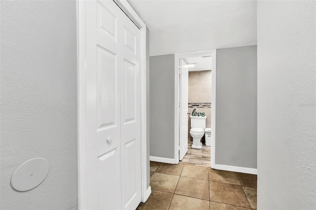 hall with light tile patterned floors and a textured ceiling