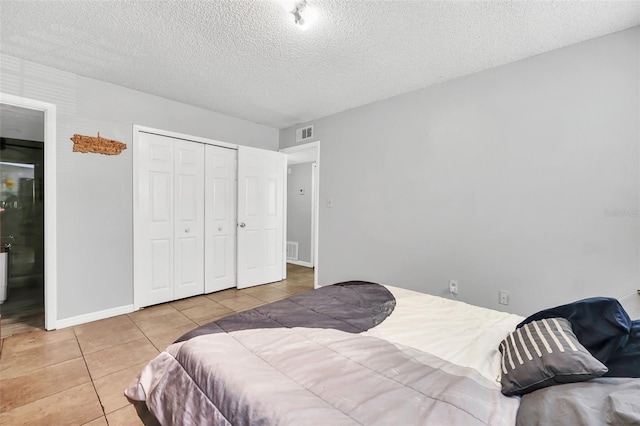 tiled bedroom featuring a closet and a textured ceiling