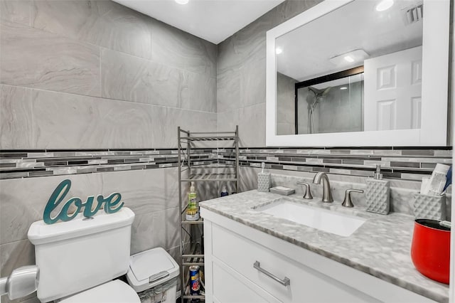 bathroom featuring vanity, tile walls, and toilet