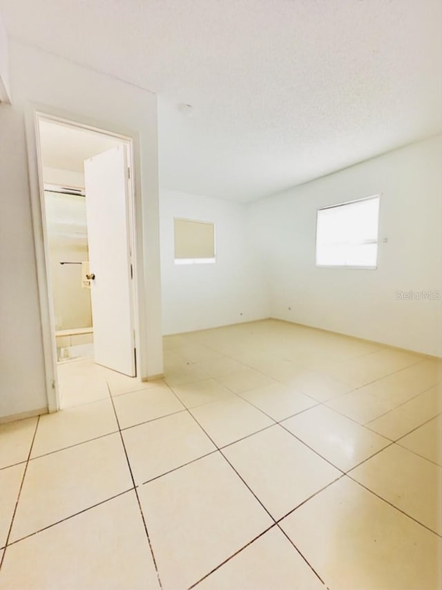 spare room featuring a textured ceiling and light tile patterned floors