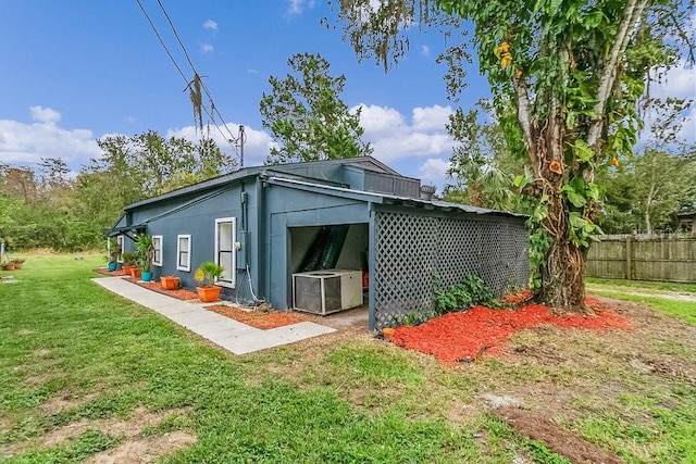 back of property featuring central air condition unit and a yard