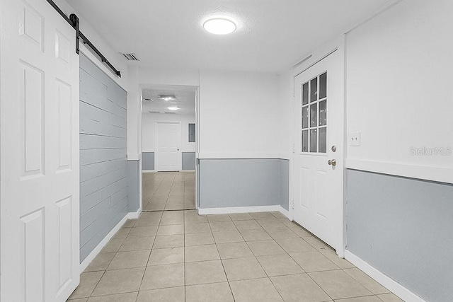 hallway with a barn door and light tile patterned floors