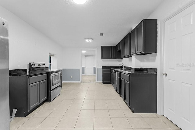 kitchen featuring light tile patterned floors, stainless steel electric stove, and sink