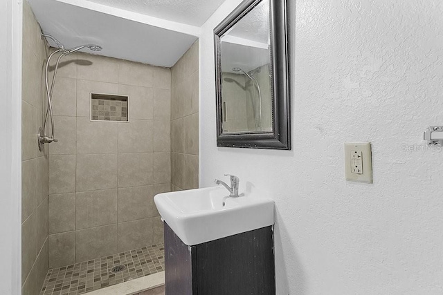 bathroom featuring tiled shower and vanity
