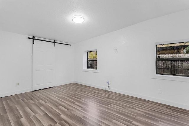 spare room featuring a barn door, light wood-type flooring, and a textured ceiling