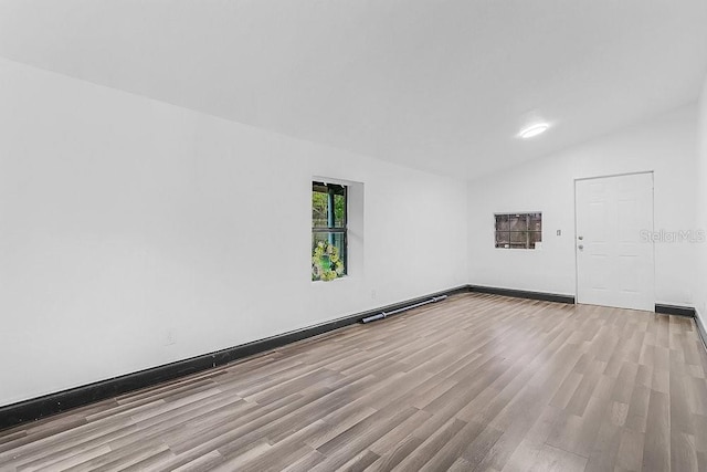 unfurnished room featuring light wood-type flooring and vaulted ceiling