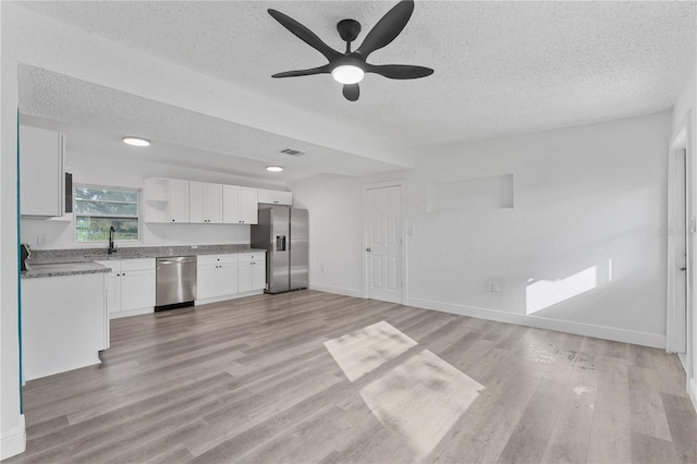 kitchen with light hardwood / wood-style flooring, stainless steel appliances, white cabinetry, a textured ceiling, and ceiling fan