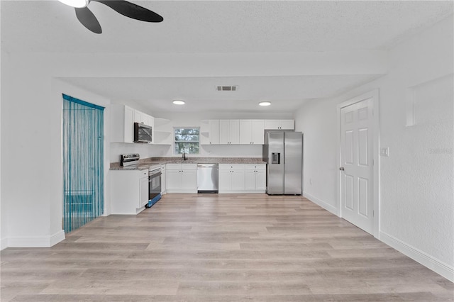 kitchen featuring appliances with stainless steel finishes, white cabinets, sink, and light hardwood / wood-style floors