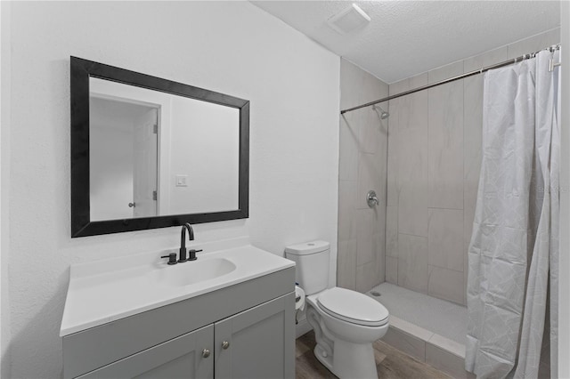 bathroom featuring hardwood / wood-style floors, a textured ceiling, toilet, vanity, and a shower with shower curtain