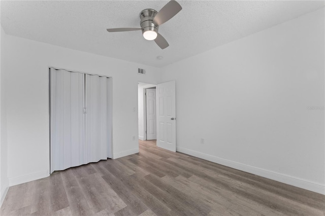 unfurnished bedroom with a closet, ceiling fan, a textured ceiling, and light hardwood / wood-style floors